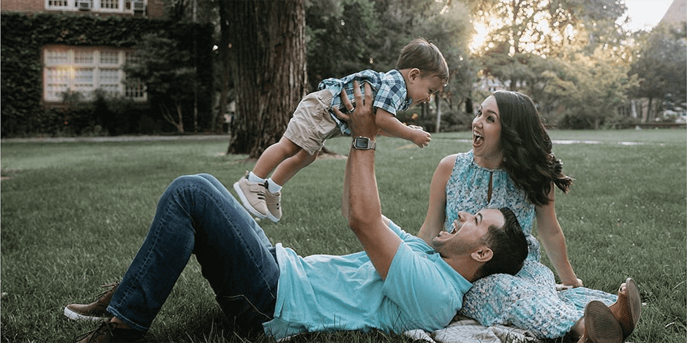 Couple in the park with the father holding a baby aloft