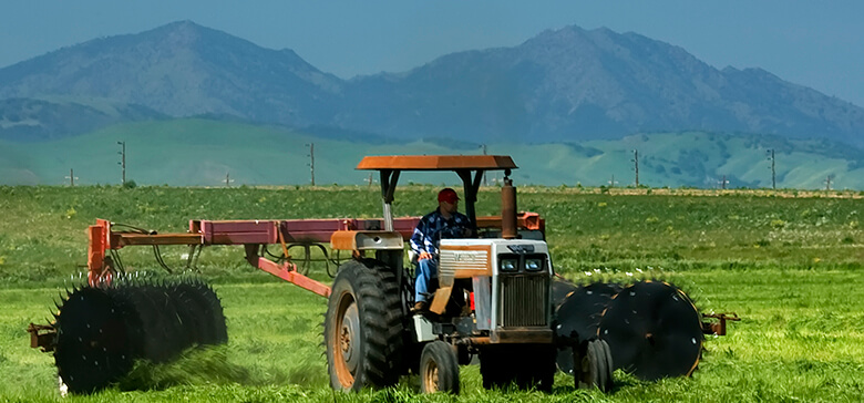 Farmer on a tractor with mountains behind