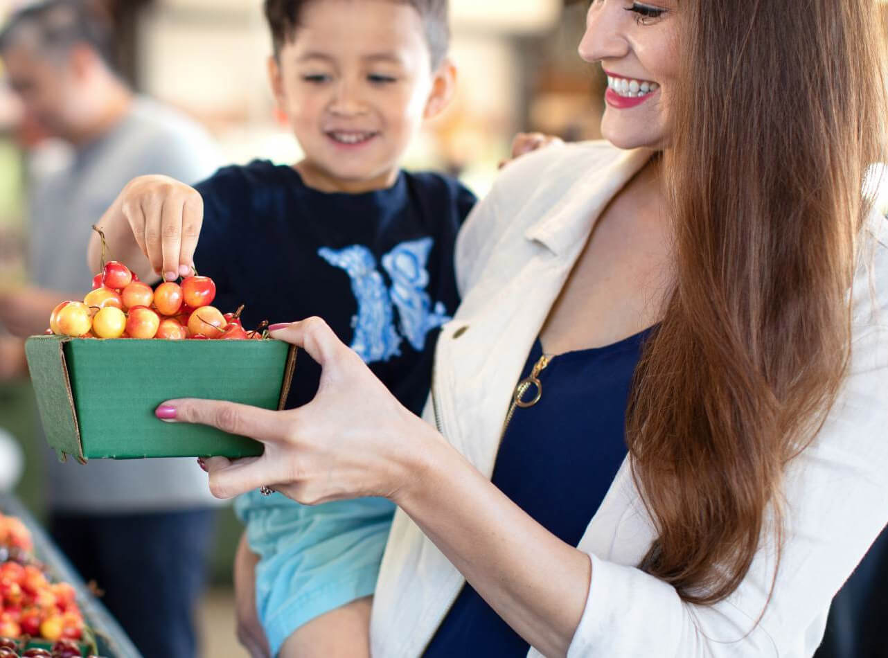 Mother holding her son and eating cherries