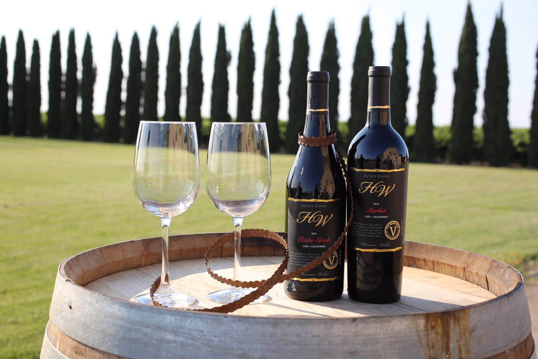 Wine Bottles on a barrel next to wine glasses